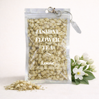 Packaged jasmine flower tea with a keychain and jasmine flowers on a white background