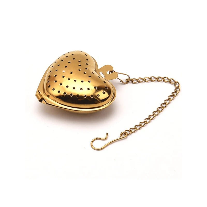 Gold heart-shaped tea infuser with a chain on a white background