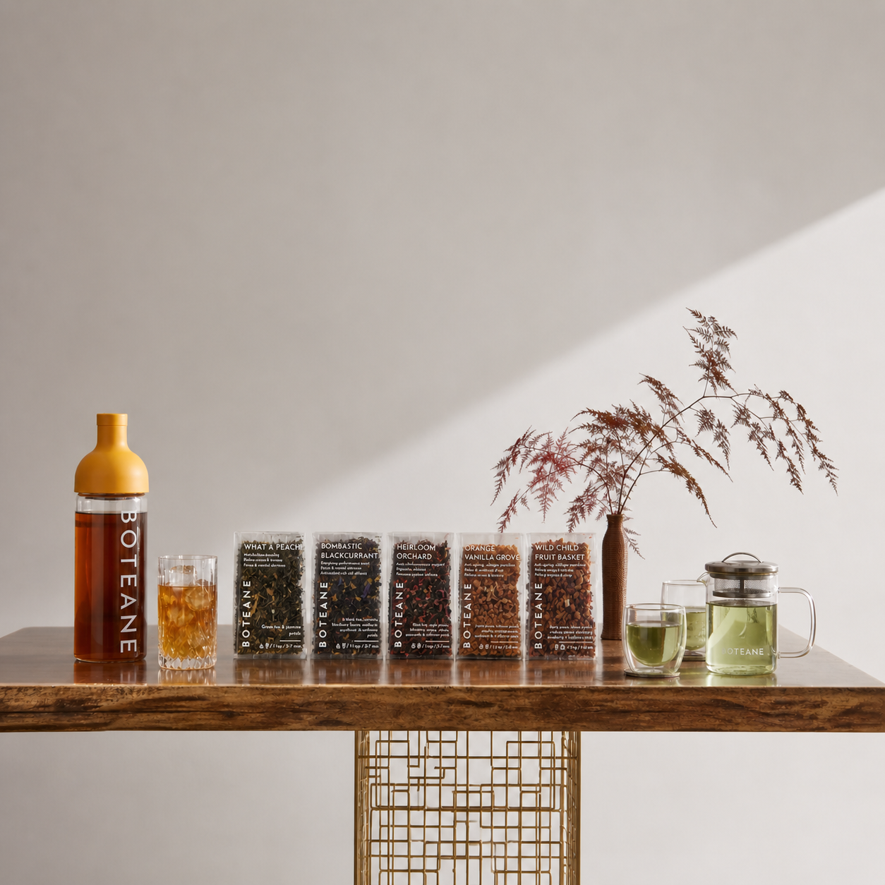 Boteane products on a wooden table with glasses of tea and a vase with dried plants.