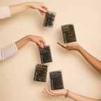 Hands holding packages of Botane Flower Power products on a beige background