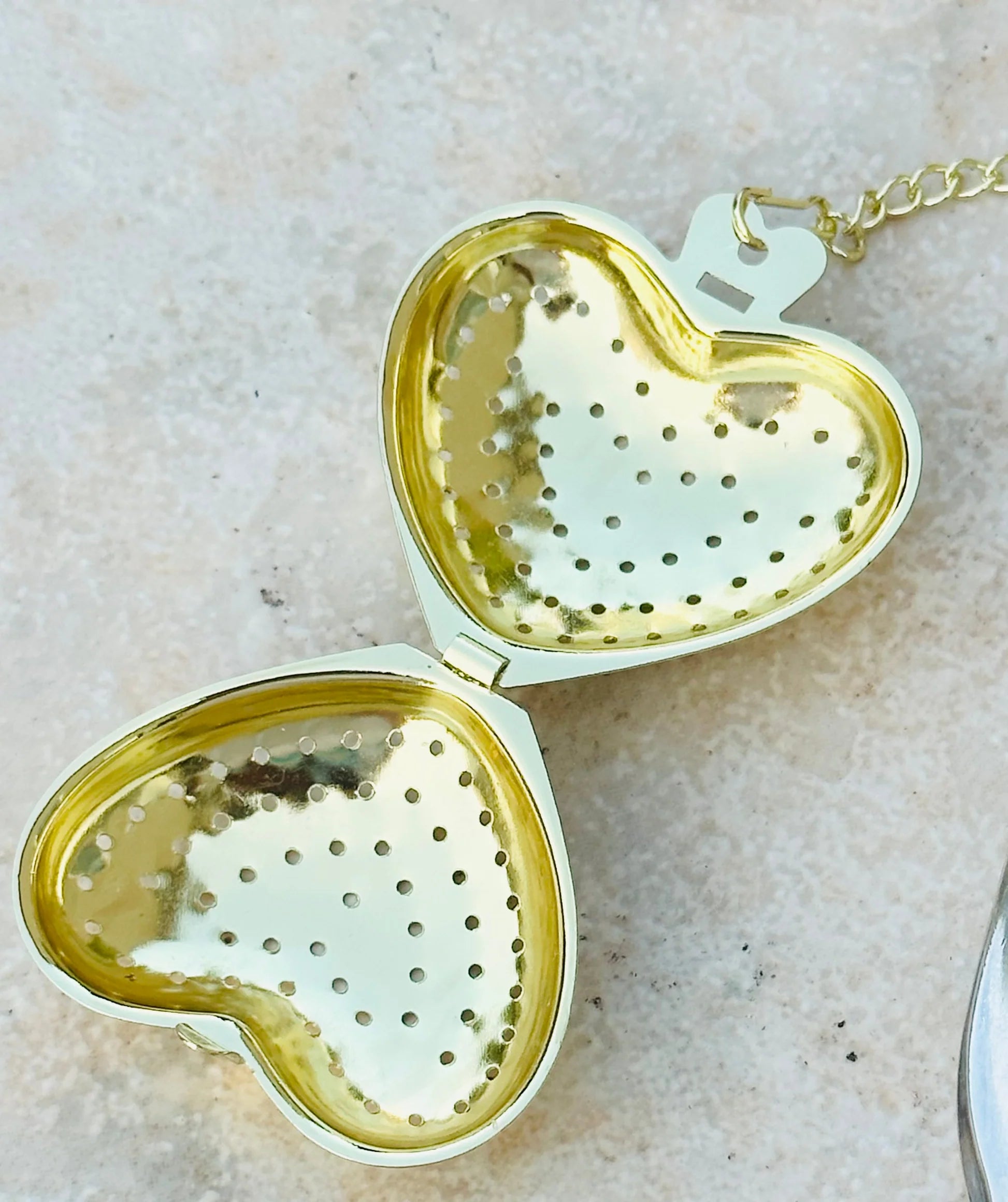 Heart-shaped gold tea infuser on a light background